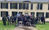 Park and Bark rangers at Saratoga NHP standing in front of building holding commemorative flag. 