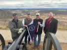 Four people holding the commemorative flag at an overlook point