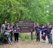 Group standing in front of trail sign with commemorative flag. 
