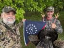 Two hunters with a turkey holding the commemorative flag
