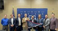 Group of people holding 250 flag in front of blue SBA sign. 