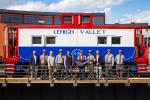 Group of people holding 250 flag in front of steam train