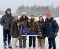 Group of people in snowy weather holding commemorative flag