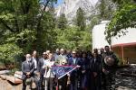 Group of people holding commemorative flag in front of iconic Yosemite Valley landscape