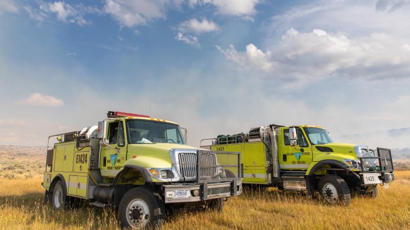Two wildland fire engines parked in a meadow