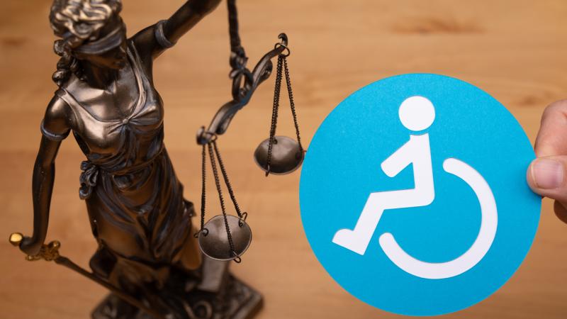 A statue of a woman with scales as the symbol of law and the disabled people sign. 