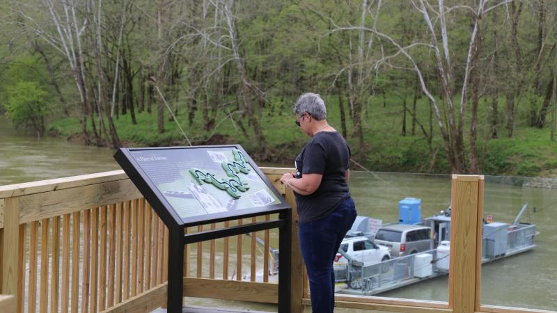 A visitor to Mammoth Cave National Park engages the wayside exhibit at the Green River Ferry Overlook along the Echo River Springs Trail.