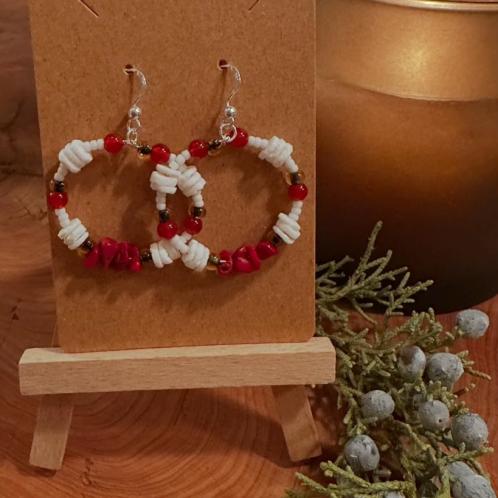A pair of red and white beaded earrings handing on a stand.