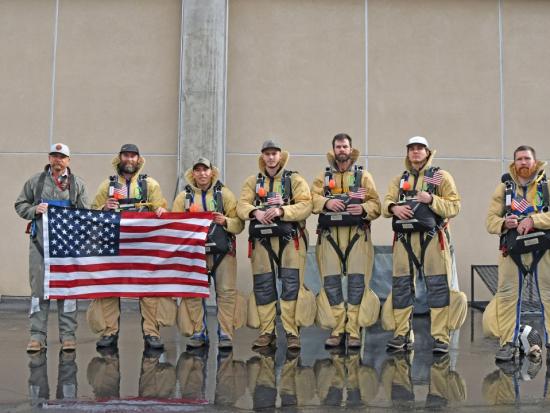 Smokejumpers hold a U.S. flag before departing for a Canada wildfire assignment. 