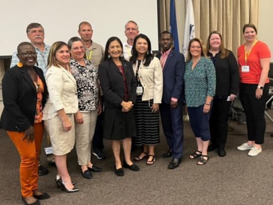 Commission members pose for a photo with Secretary Haaland. 