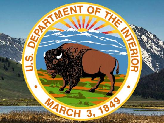 Department of the Interior bison seal set against green mountainous background.