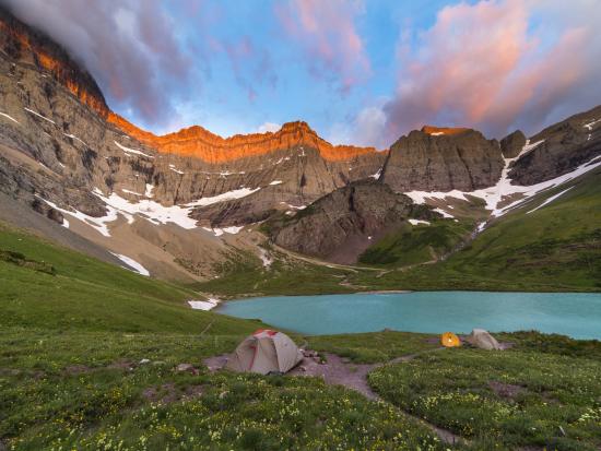 tents camped near a blue lake surrounded by mountains