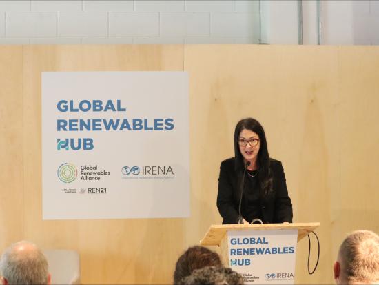Assistant Secretary Estenoz speaking at podium in front of a sign reading Global Renewables Hub