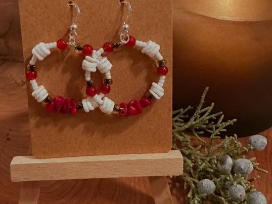 A pair of red and white beaded earrings handing on a stand.