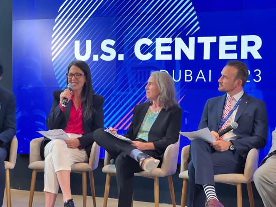 Assistant Secretary Estenoz and two others sitting on a stage speaking to audience