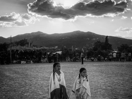 Black and white photo of two children with cloudy skies and mountains