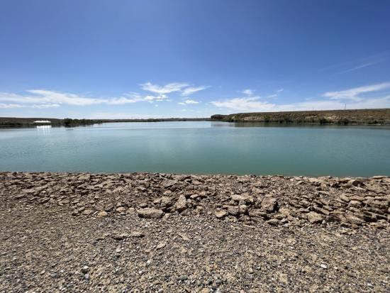 Rocky shoreline and water reflecting blue sky. 