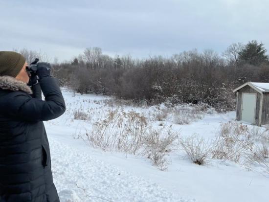 Secretary Haaland uses binoculars to get a closer look at a wintery landscape in New Hampshire