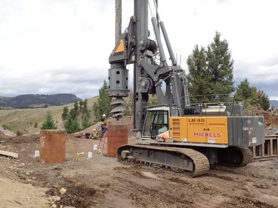 Yellow construction machinery at work to build the foundation of the new bridge