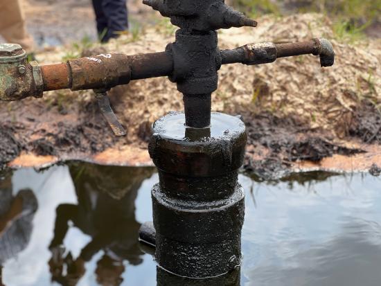 Rusting well pump surrounded by a muddy puddle. 