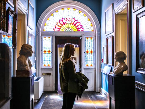 Visitor in a hallway with numerous paintings and busts of suffragists
