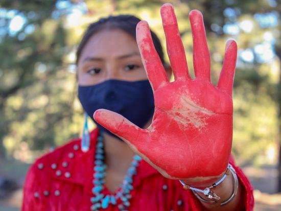 Woman holding up red painted hand