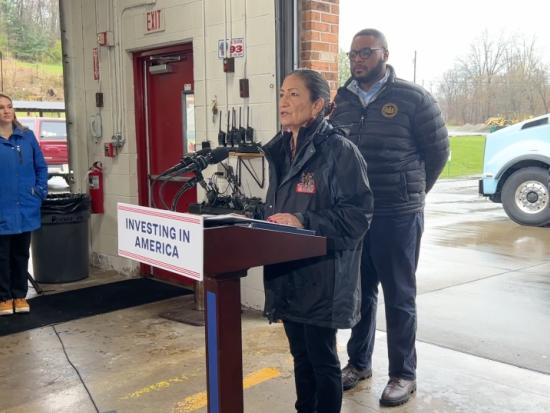 Secretary Haaland standing behind a podium with the sign Investing in America during a visit to Arkansas 