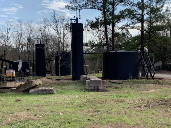 Black orphaned well equipment in grassy area. 