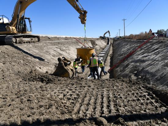Construction workers with equipment in ditch. 