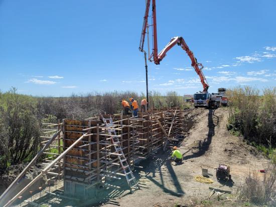 Constructions workers on top of wooden structure with crane in background.