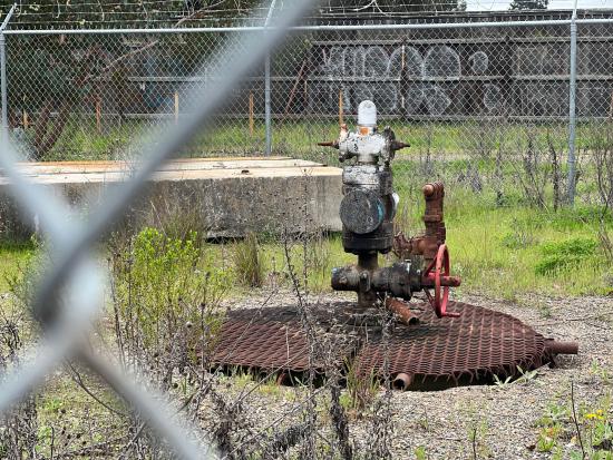 Orphaned oil and gas well behind a chain link fence