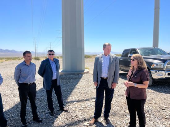 4 people talking to each other in front of truck and desert landscape 
