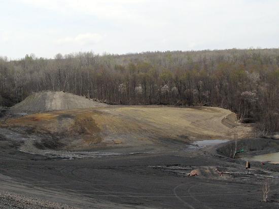 Area with dark soil and mounds of dirt with construction crew. 