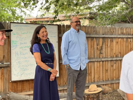 Secretary Haaland laughing with others in front of a dry erase board. 