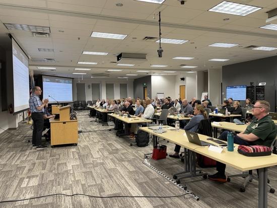 A man presents to a room full of people
