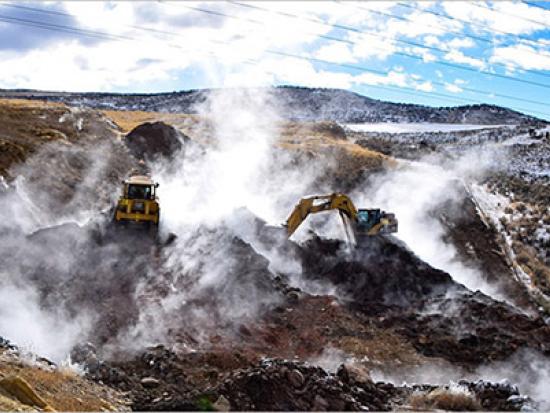 Construction equipment in high desert landscape with cloudy sky. 