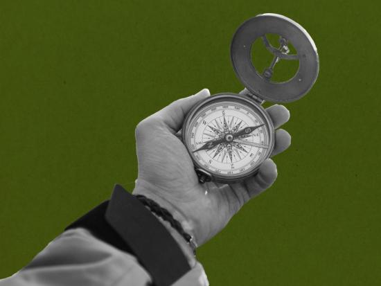 Hand holding compass on green background