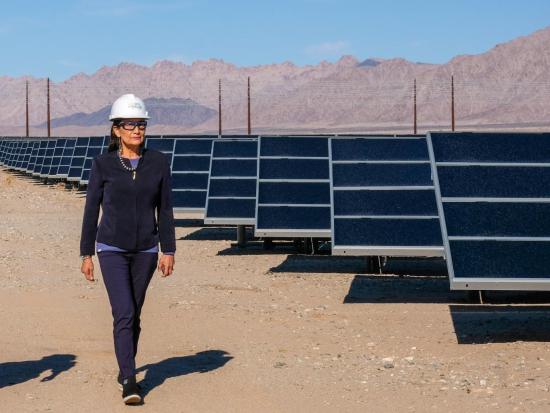Secretary Haaland in hard hat walking next to solar panels. 