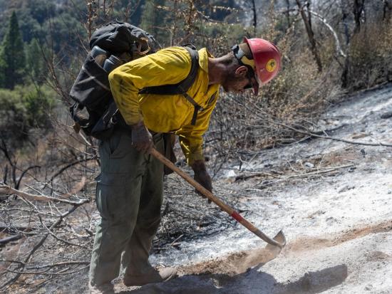 A wildland firefighter on the Midnight Sun Hotshot crew checks for hot spots on an active fireline. Photo from the Coffee Pot Fire on Inciweb.  
