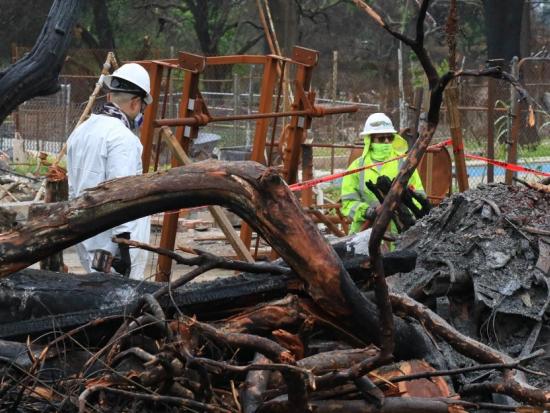 Two people cleaning up debris from wildfire.
