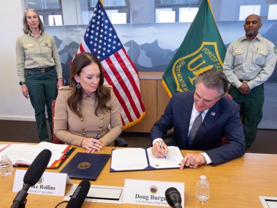 Secretary Burgum signing joint fire memo at a table.