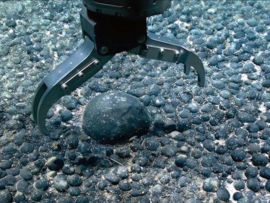 Crane arm in water reaching for silverish rock like alloy.
