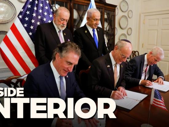 Secretary Burgum with heads of state and international officials in business attire in a formal setting signing documents on a brown table