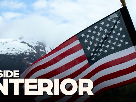 An American flag in front of snow capped mountains