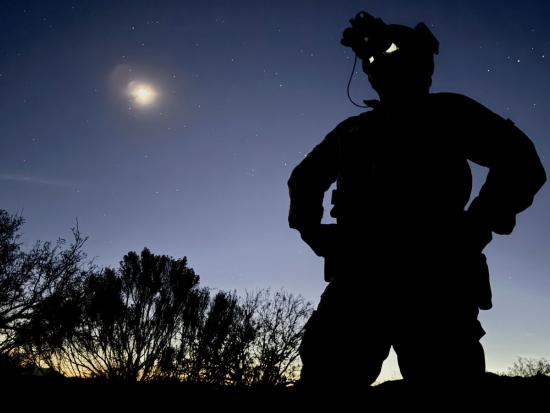 Border patrol agent illuminated by moonlight
