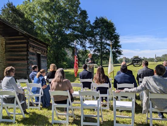 Superintended Brad Bennett providing remarks to a crowd seated in front of the re-created Brotherton Cabin in Chickamauga Battlefield