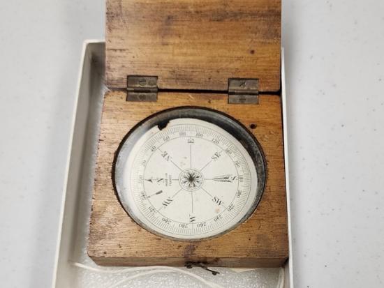 A wooden compass in a white box. 