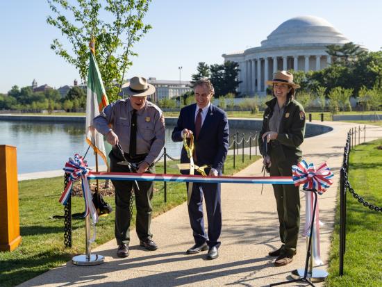 Secretary Burgum and two park rangers cutting red white and blue ribbon at ribbon cutting ceremony. 