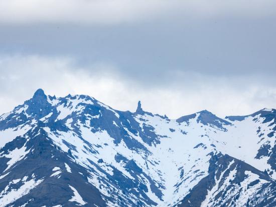 Snow capped jagged mountain tops and cloudy skies