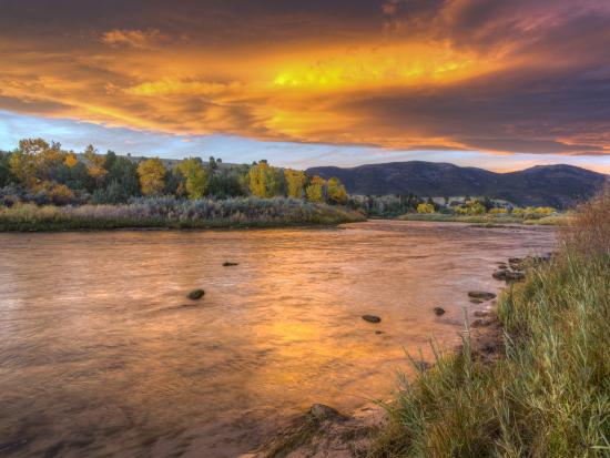 Orange and dark purple sky reflects on the Green River. 